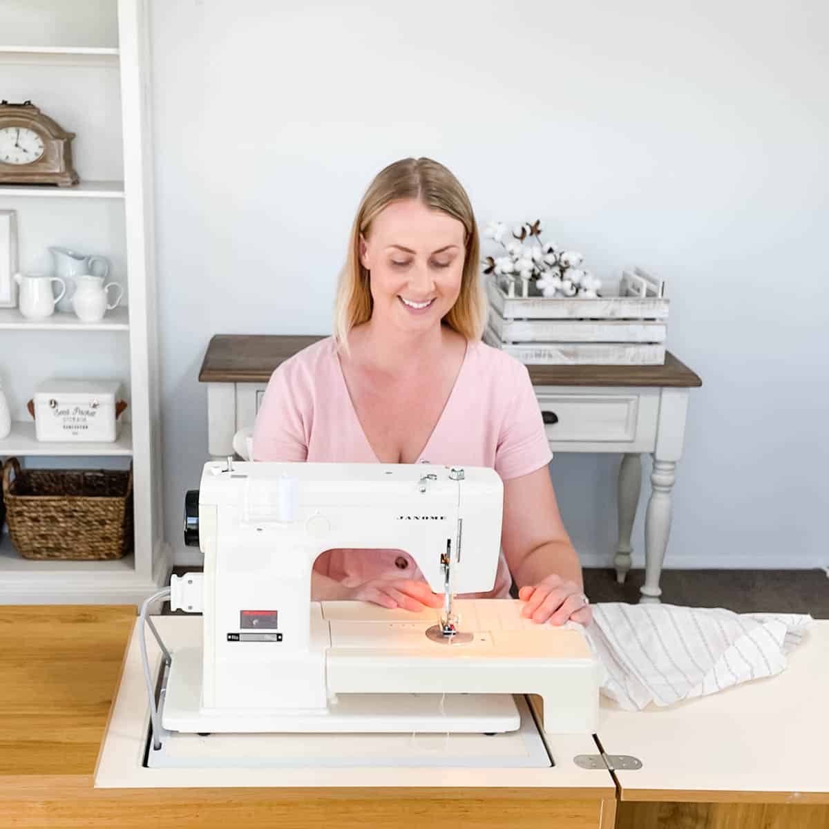 Image of Emily sitting at the sewing machine sewing white and blue striped fabric