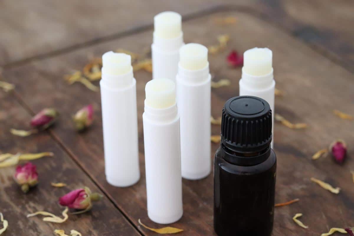 Image of a group of lip balm tubes filled with essential oil lip balm next to a bottle of essential oils