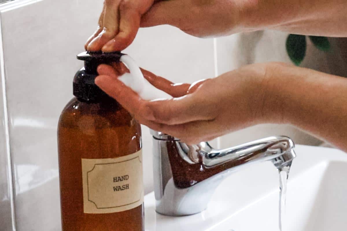 Close up image of hands using foaming pump dispenser to apply hand soap