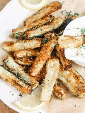 Overhead image of a plate of zucchini fries and a small bowl of aioli sauce