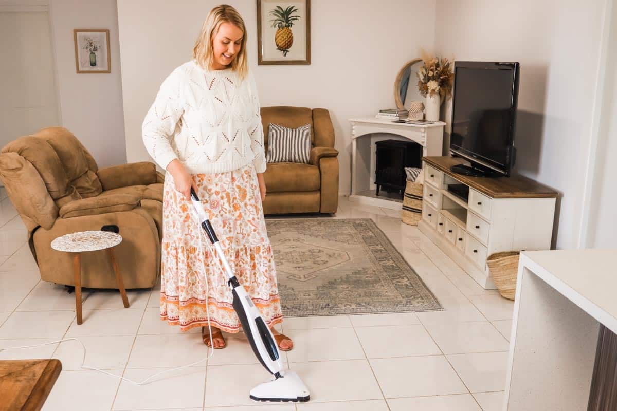 Image of Emily in the living room using the steam mop on a tiled floor