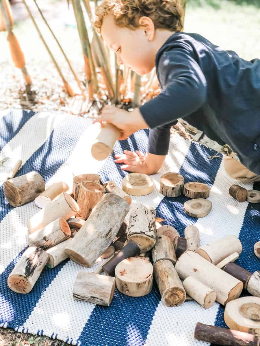 Image showing getting stuff done with toddler William is happily distracted playing with pieces of timber laid out on a blue and white rug