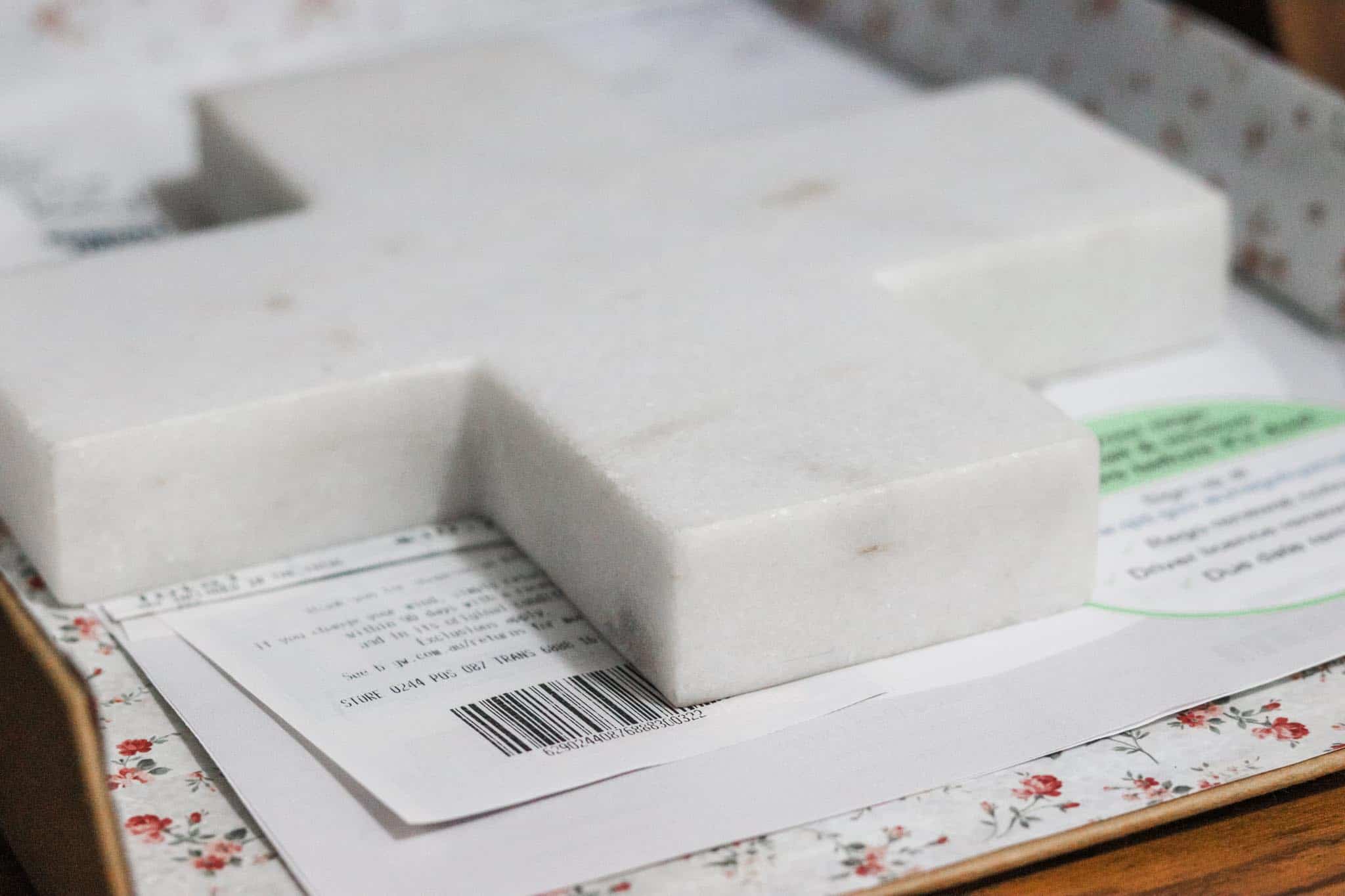 Close up image of a cardboard in tray holding paperwork with a marble cross shaped paper weight
