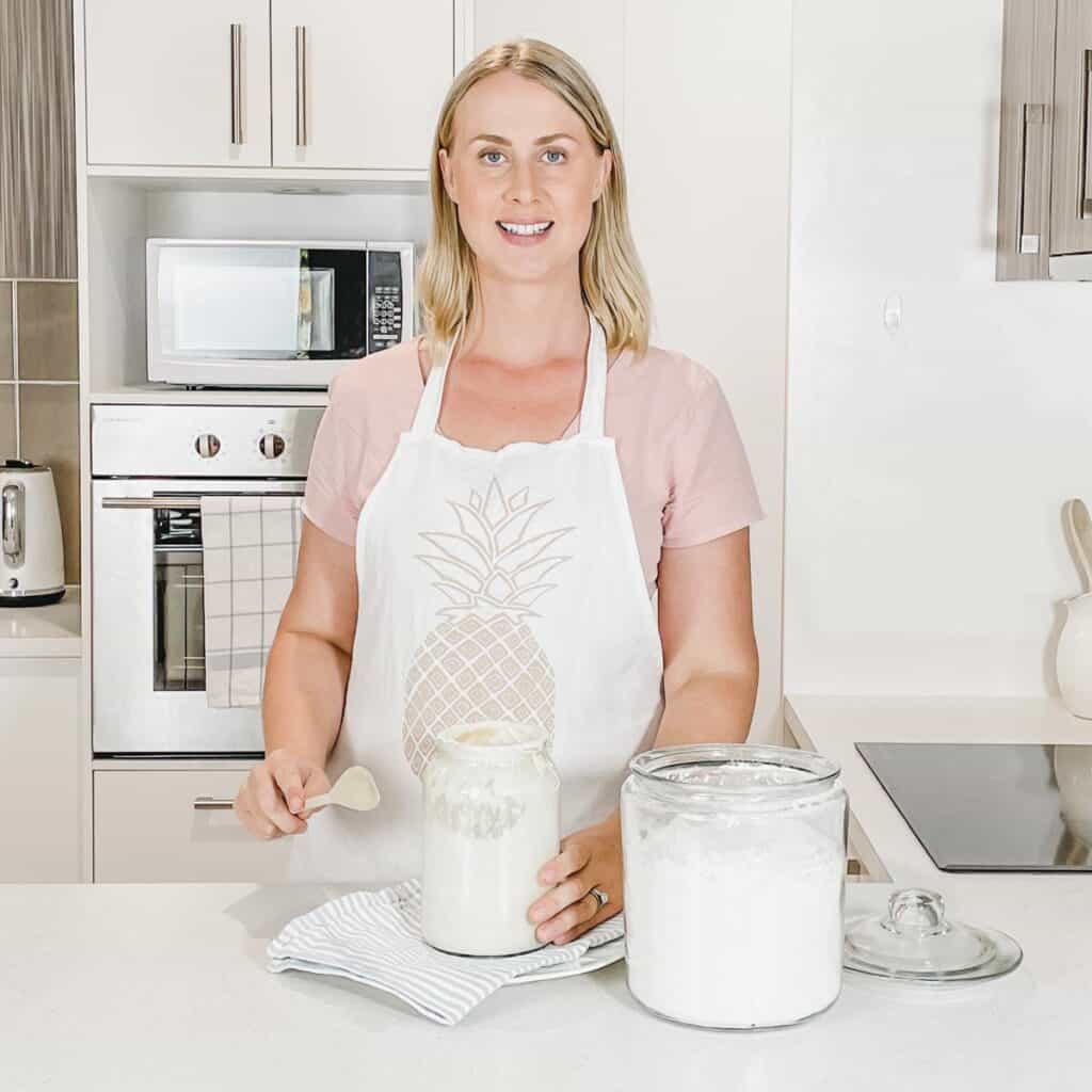 Image of Emily in the kitchen mixing a jar of sourdough starter