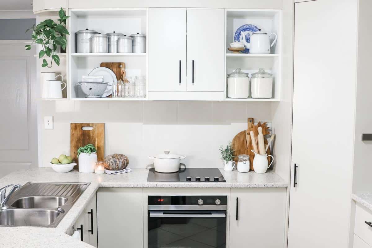 Image of a kitchen where the shelves are lined with utensils, canisters, jars and cooking equipment