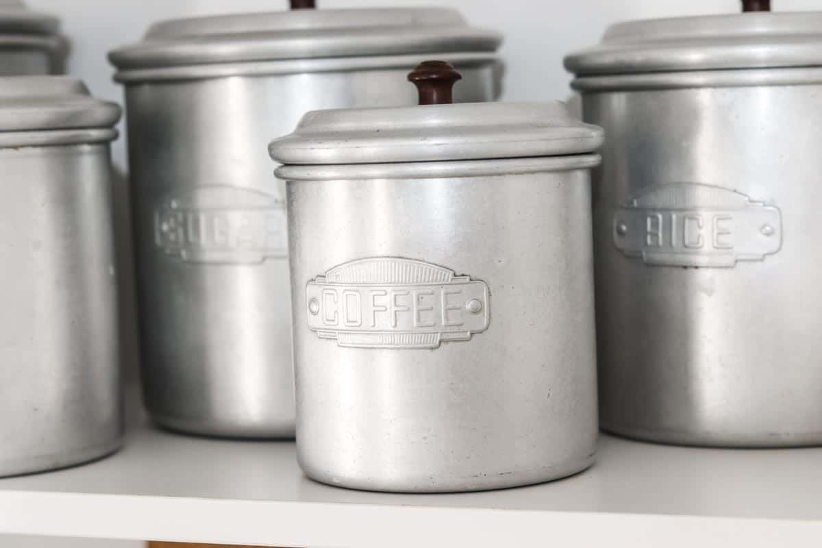 Close up image of a group of vintage aluminium ingredient kitchen canisters on a shelf