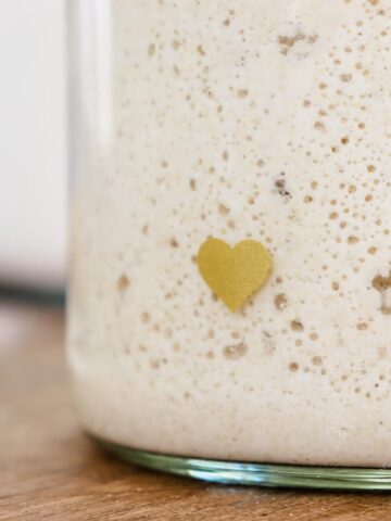 Close up image of a glass jar of sourdough starter showing bubbles