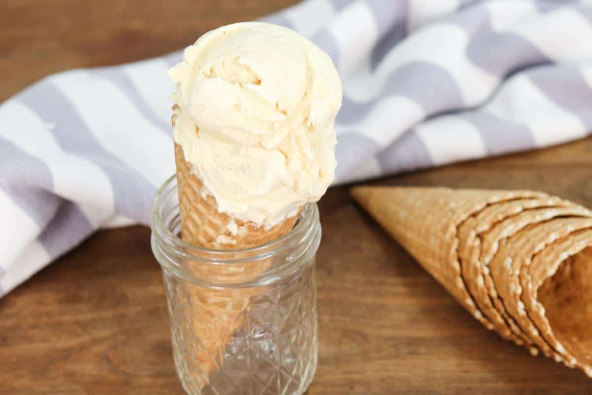 A waffle ice cream cone filled with vanilla ice cream sitting in a glass mason jar
