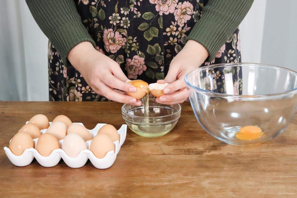 Separating the eggs white from the yolk by transferring the egg yolk between the shell over a small glass bowl