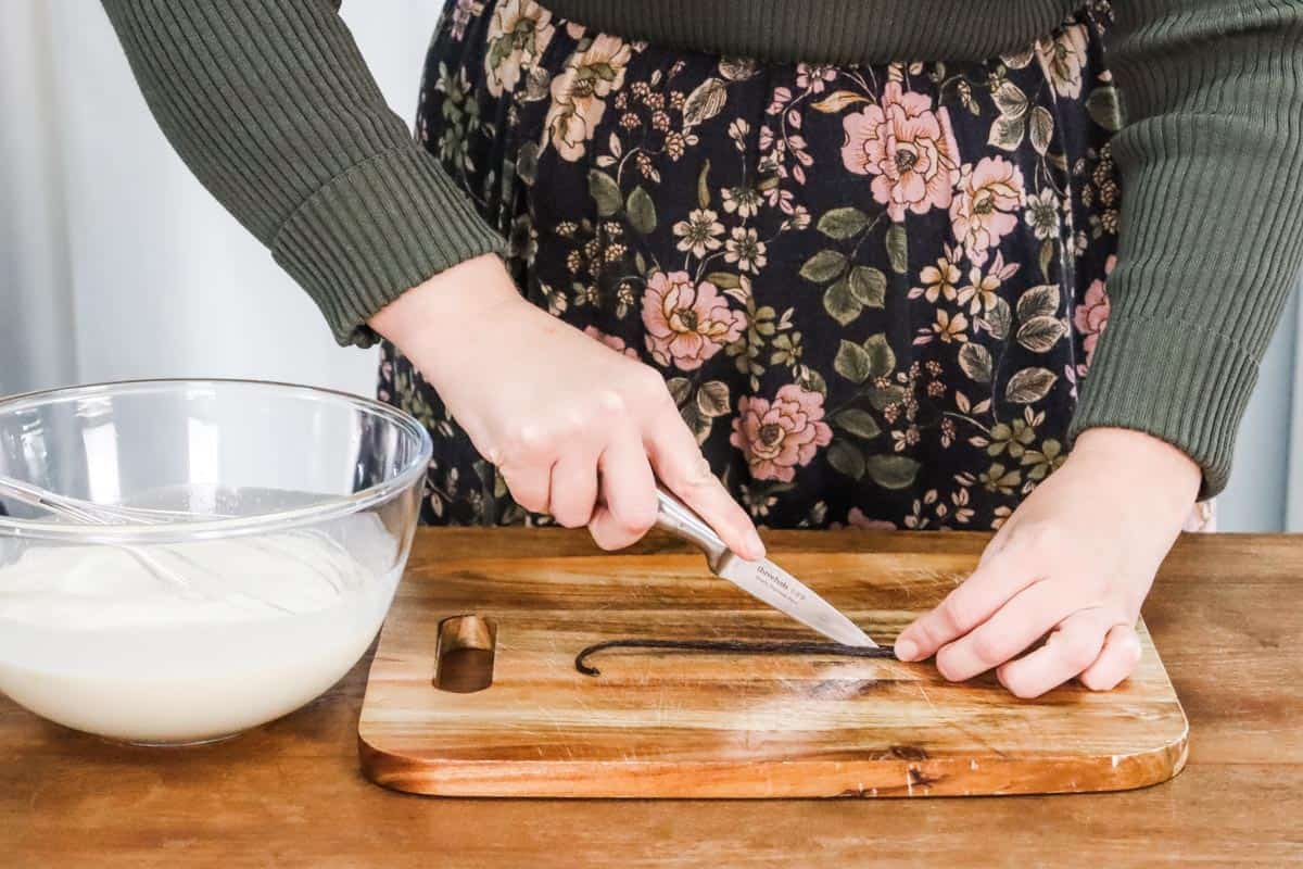 Splitting a vanilla bean using a paring knife and wooden chopping board