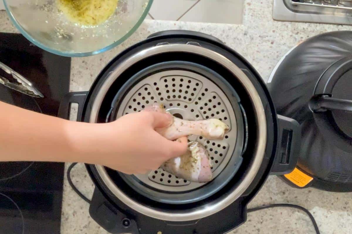 Placing raw chicken drumsticks in the air fryer basket on the top layer