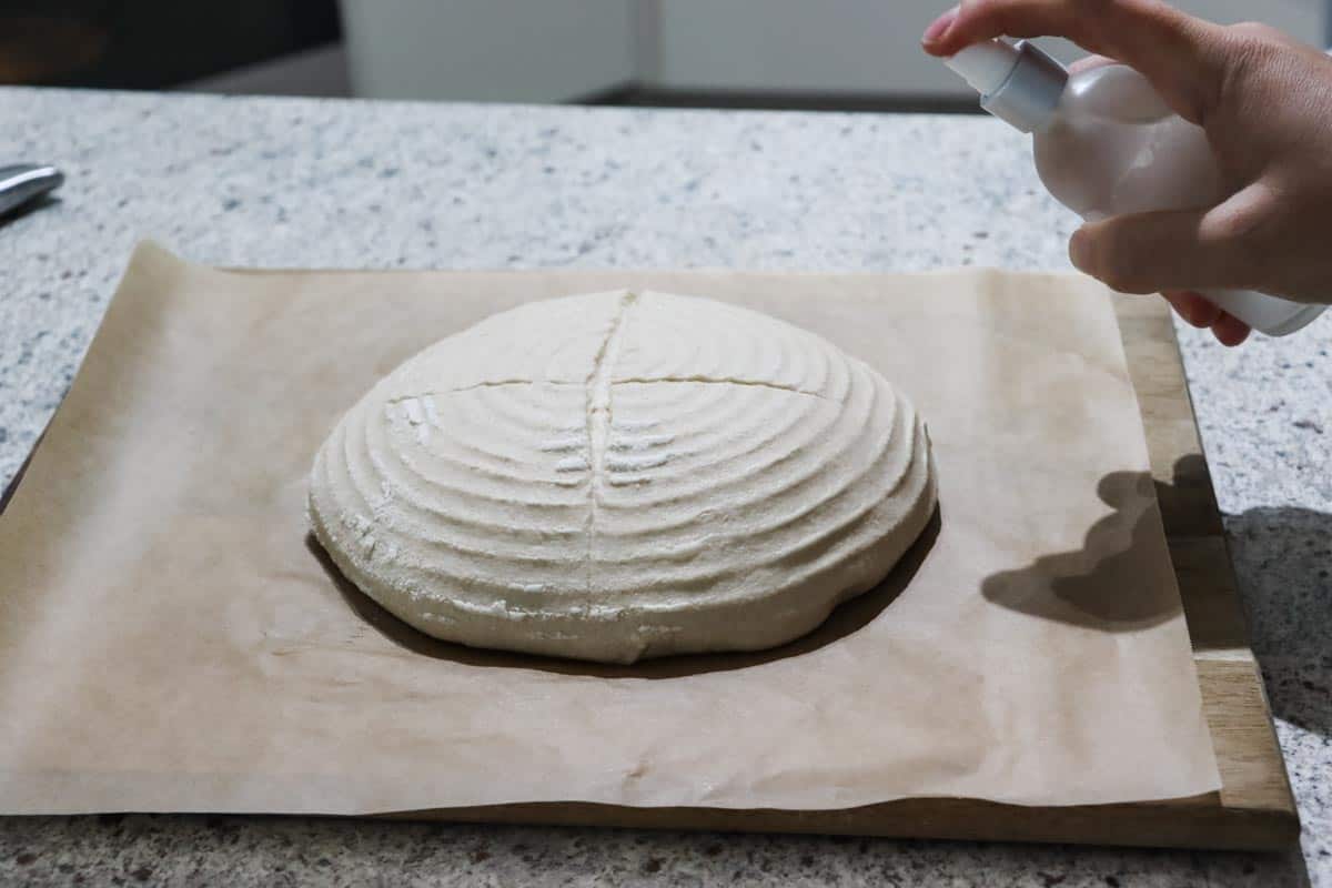 dough on a piece of baking paper being sprayed with water