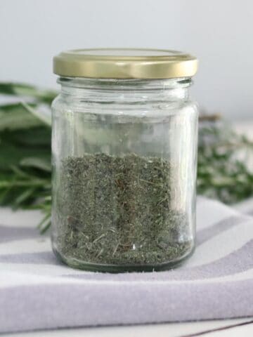 dried herbs in a jar next to fresh herbs from the garden web feature images