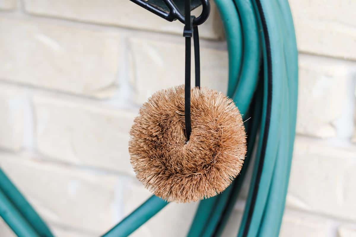 A coconut fibre brush used for keeping the chicken water clean hanging by the tap