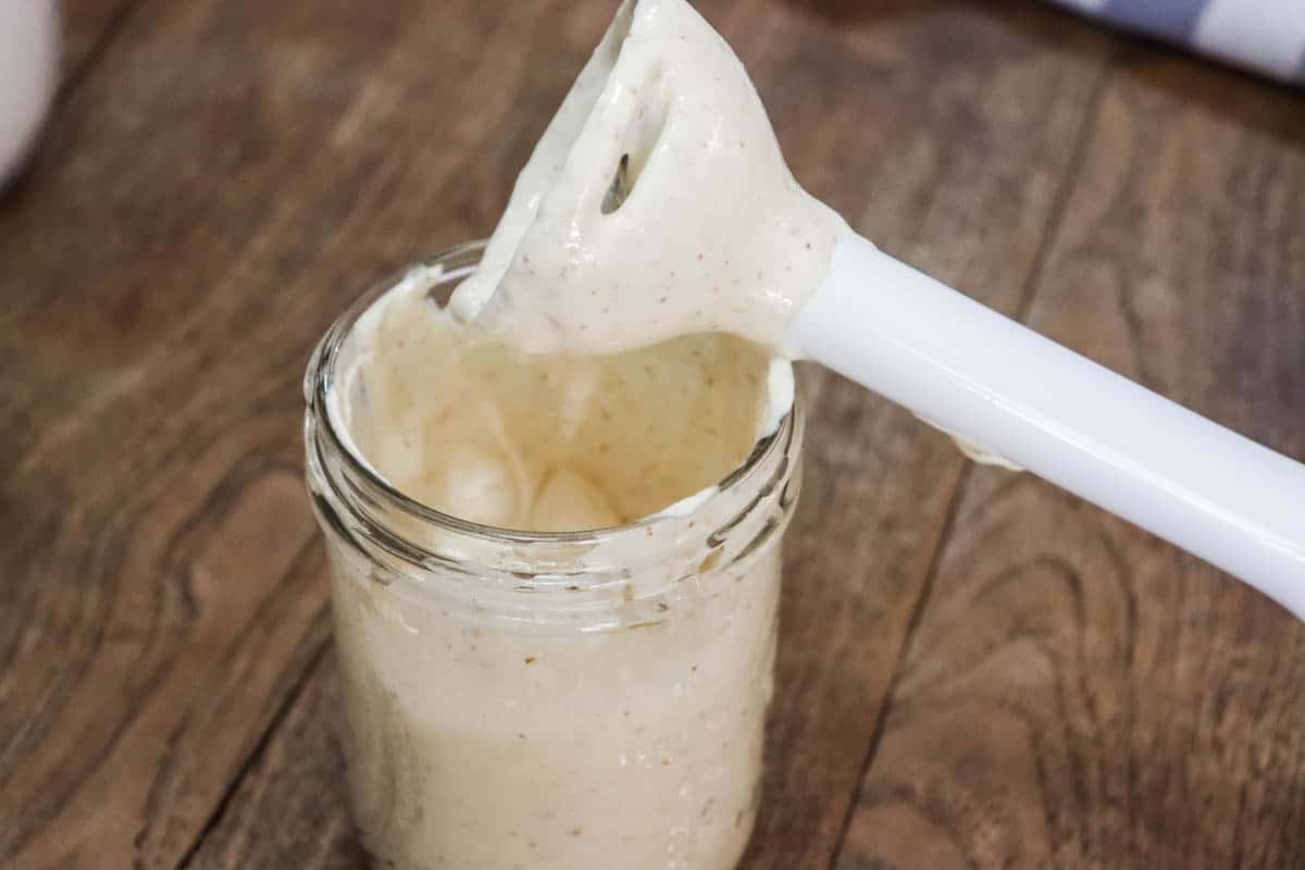 The immersion blender being tapped on the side of the jar after making mayonnaise to remove excess