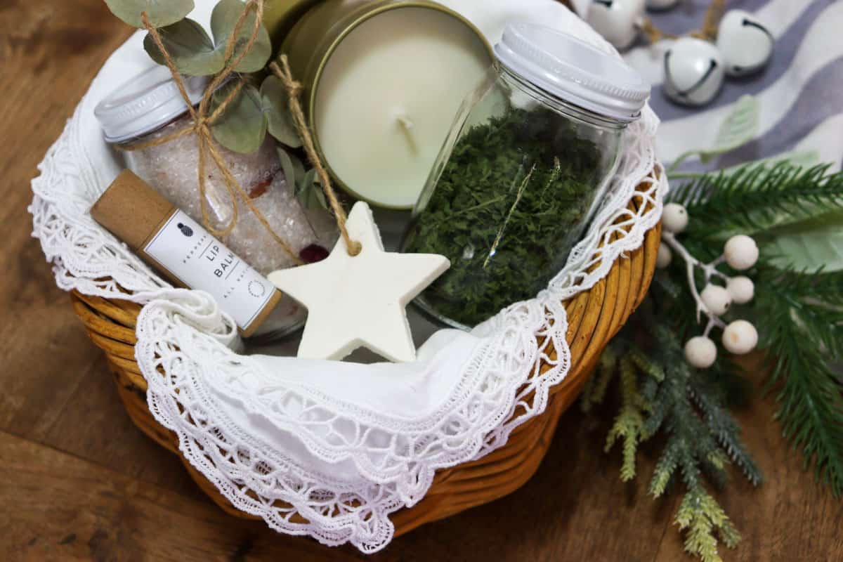 Christmas gift hamper basket with lip balm, bath salts, handmade baking soda ornament, dried herbs and a soy wax candle