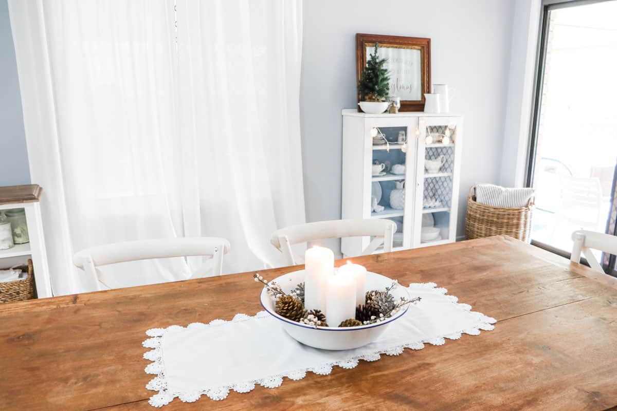 The dining table is set with a thrifted table runner and centrepiece with a china hutch in the background