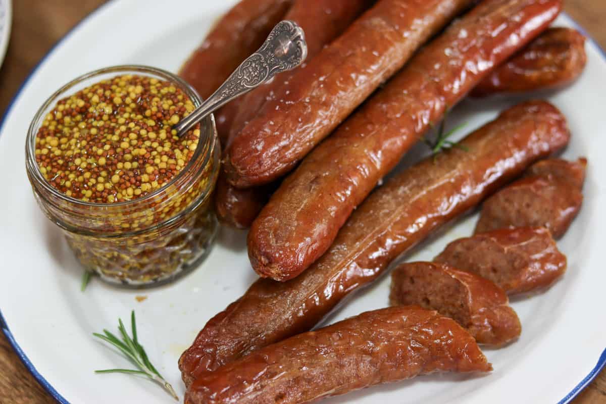 Cooked sausages on a plate with a jar of mustard