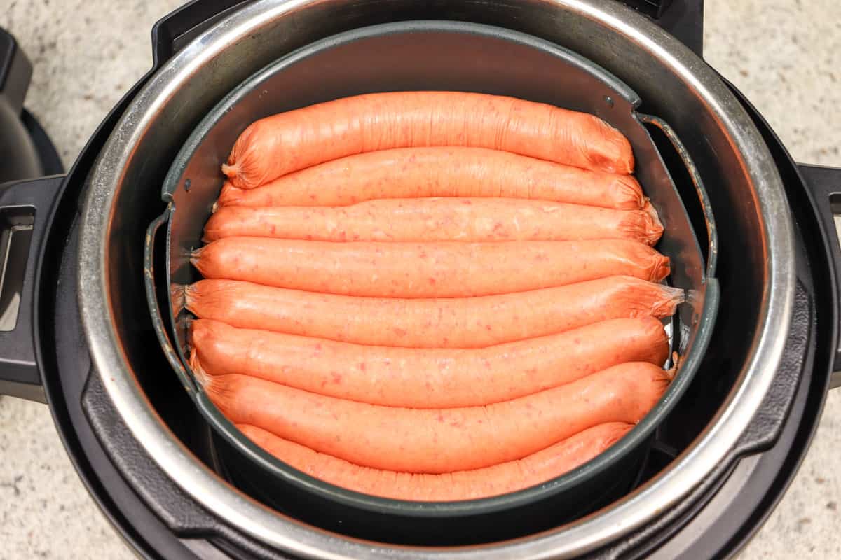 raw sausages in the air fryer basket ready to be cooked