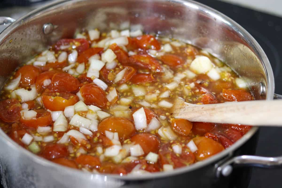 Stirring the tomato relish ingredients in the saucepan with a wooden spoon
