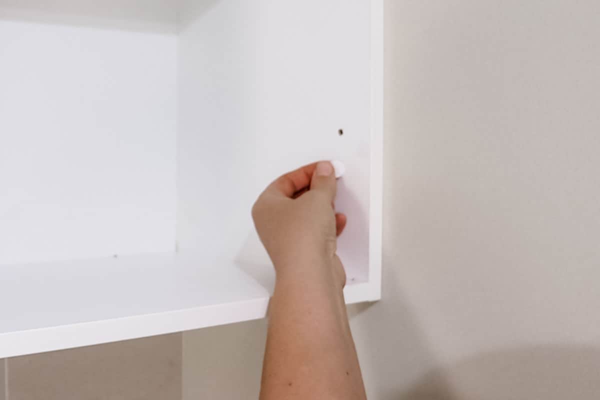 Placing stick-on screw caps on the shelving
