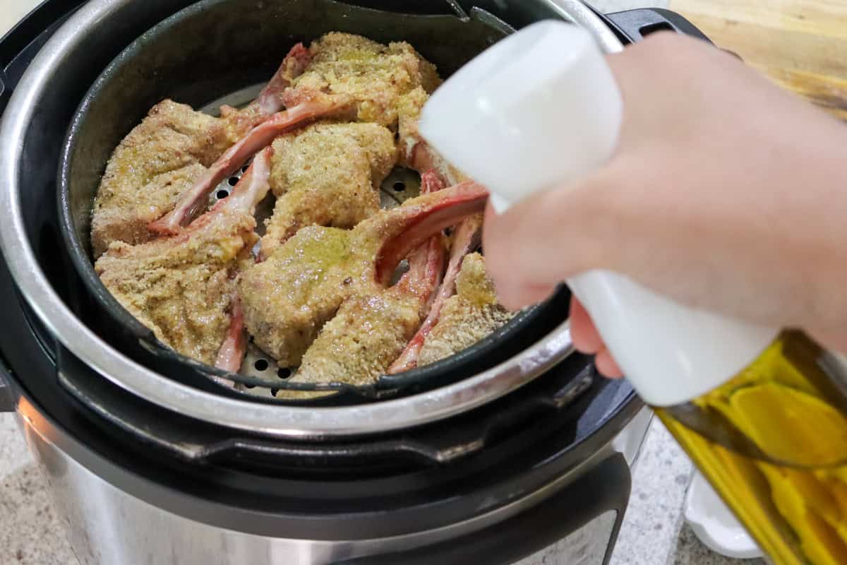 Extra virgin olive oil is sprayed on to the crumbed lamb cutlets in the air fryer before cooking