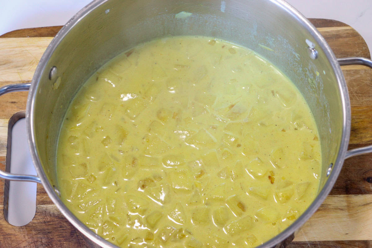 Milk is added to the saucepan and mixed with cooked onion, apple and curry powder