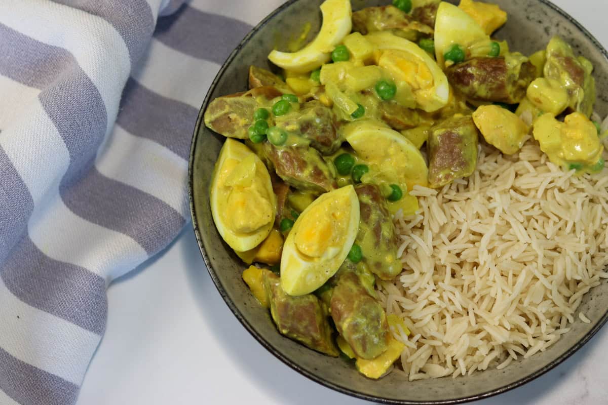Curried eggs and sausages are served in a dish with rice