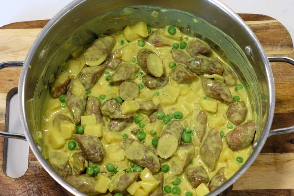 Peas are added to the sliced sausages and sauce in the saucepan