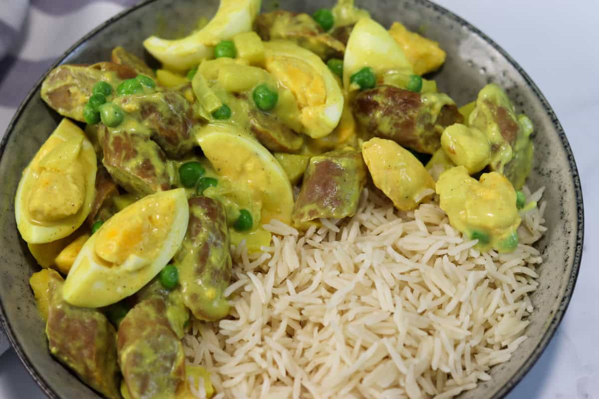 Close up image of old fashioned curried eggs and sausages plated in a dish with rice