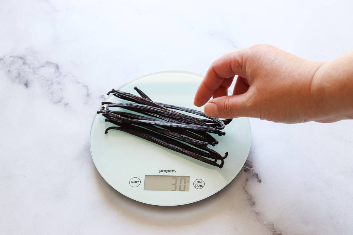 Dried vanilla beans are weighed on a digital kitchen scale