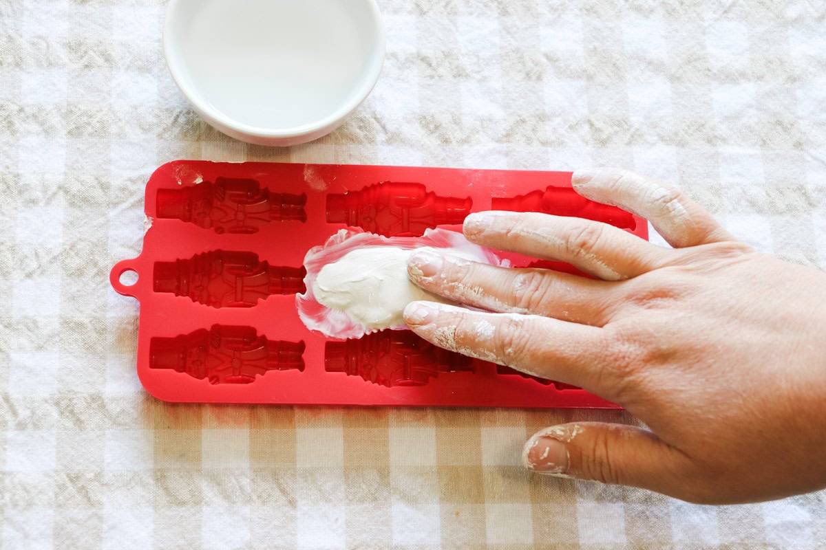 Air dry clay pressed into a silicone mould and being smoothed over by hand with water