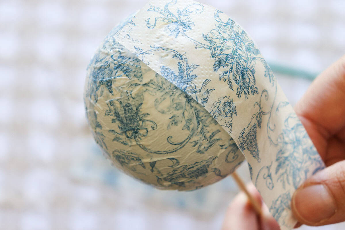 A skewer holds the bauble as the final strips of paper napkin are added to the ornament