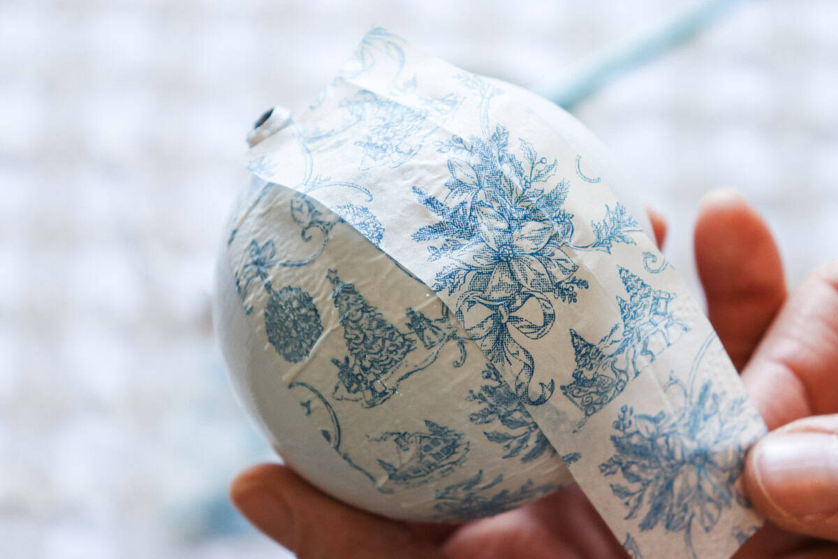 The strips of paper napkin are added to the ornament with glue