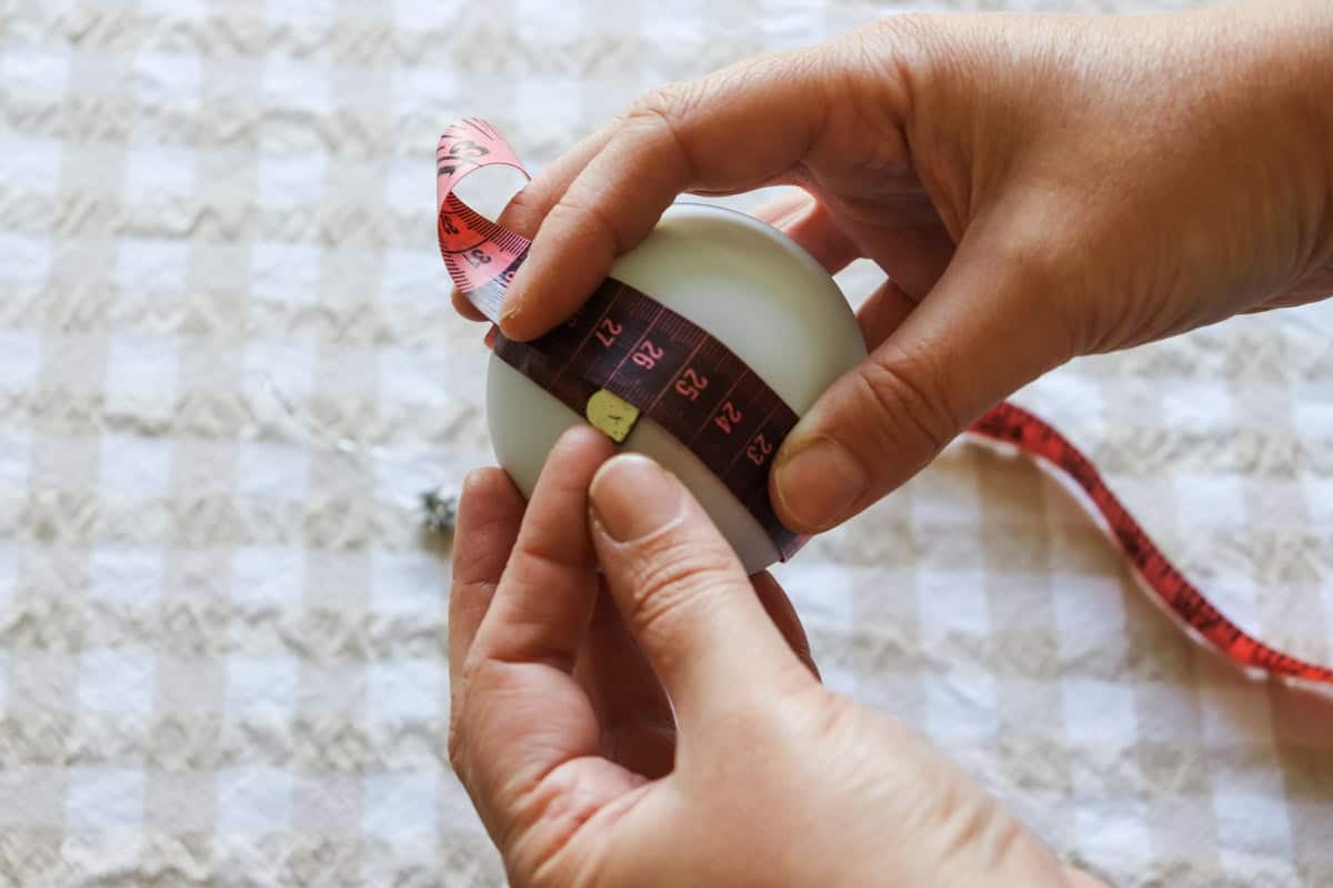 A tape measure is used to measure the circumference of the bauble