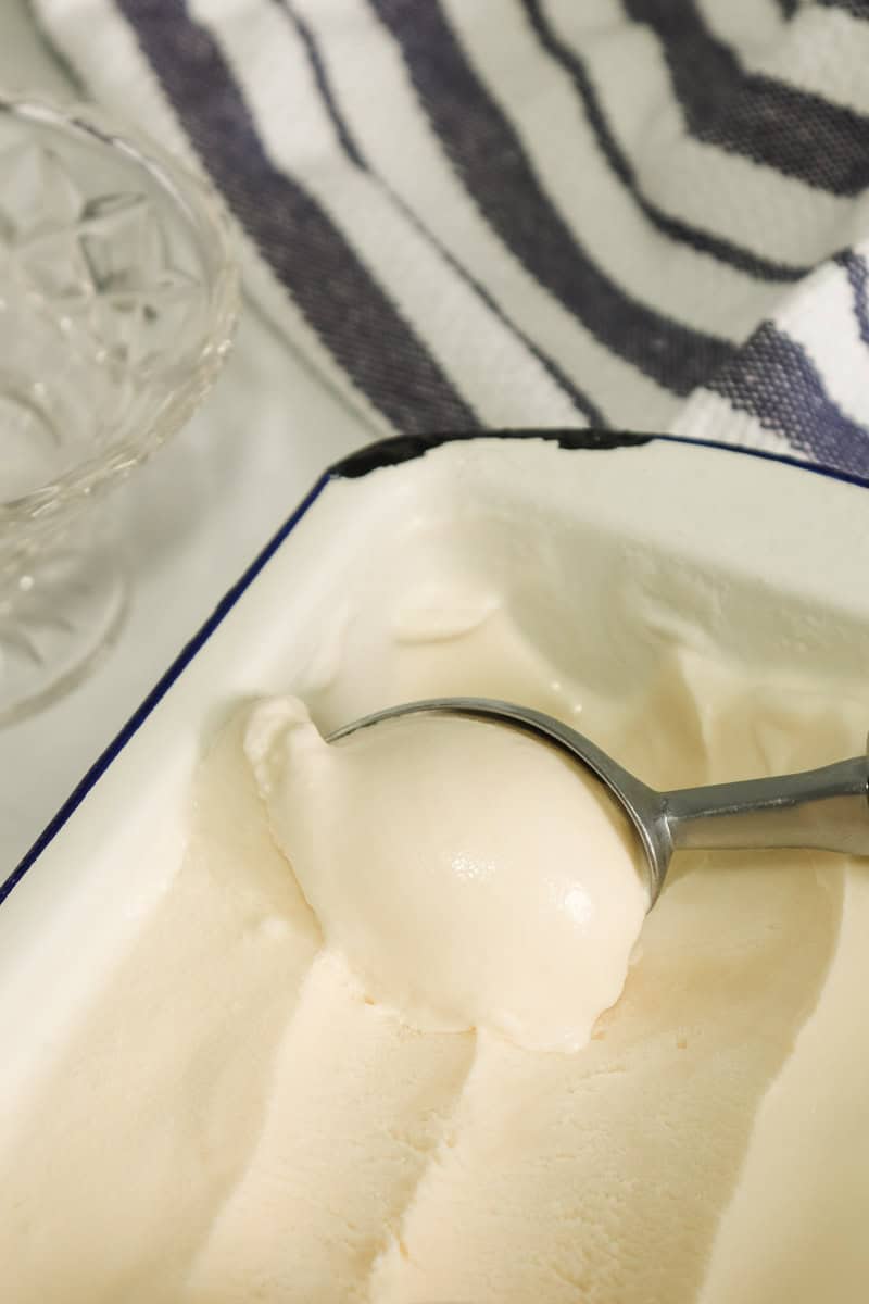 Homemade ice cream made with sweetened condensed milk is scooped out of the container with an ice cream scoop