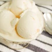 A close up image of scoops of home made ice cream with sweetened condensed milk in a bowl next to a spoon