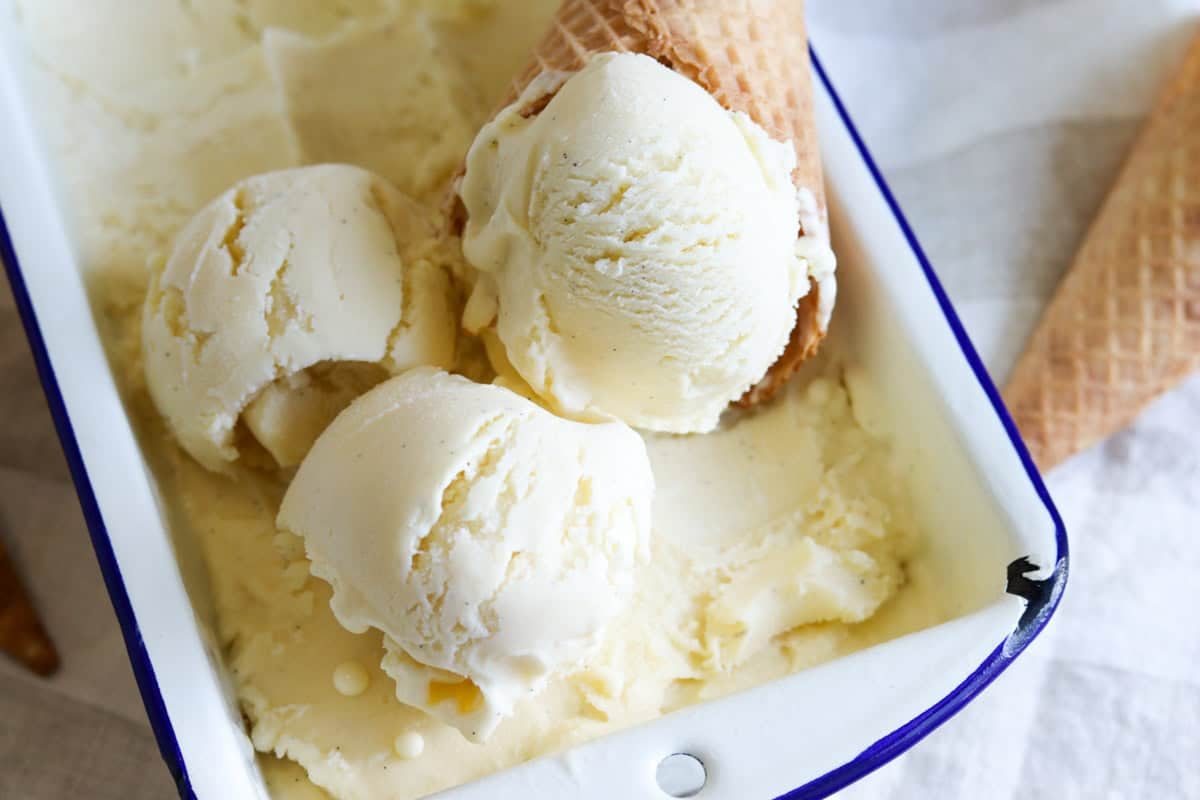 Scoops custard base vanilla ice cream in a tin with an ice cream cone