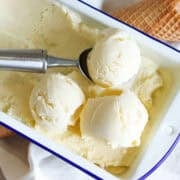 Custard base vanilla ice cream in a tin with an ice cream scoop