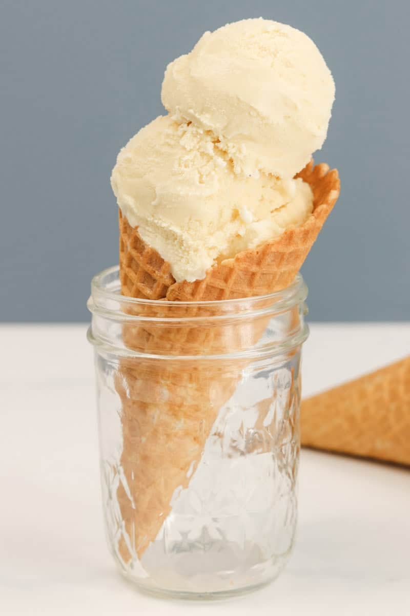The ice cream is scooped into a cone and sits in a mason jar