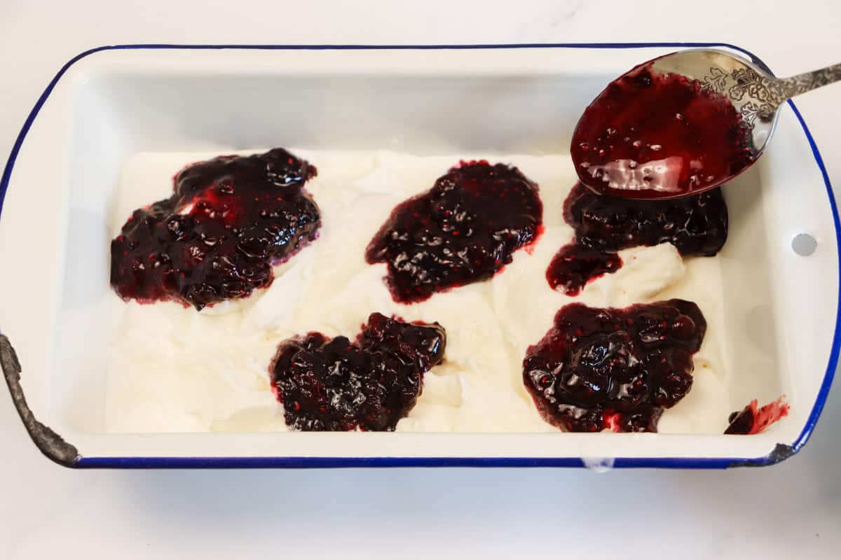 Half of the berry sauce is added to the first layer of ice cream