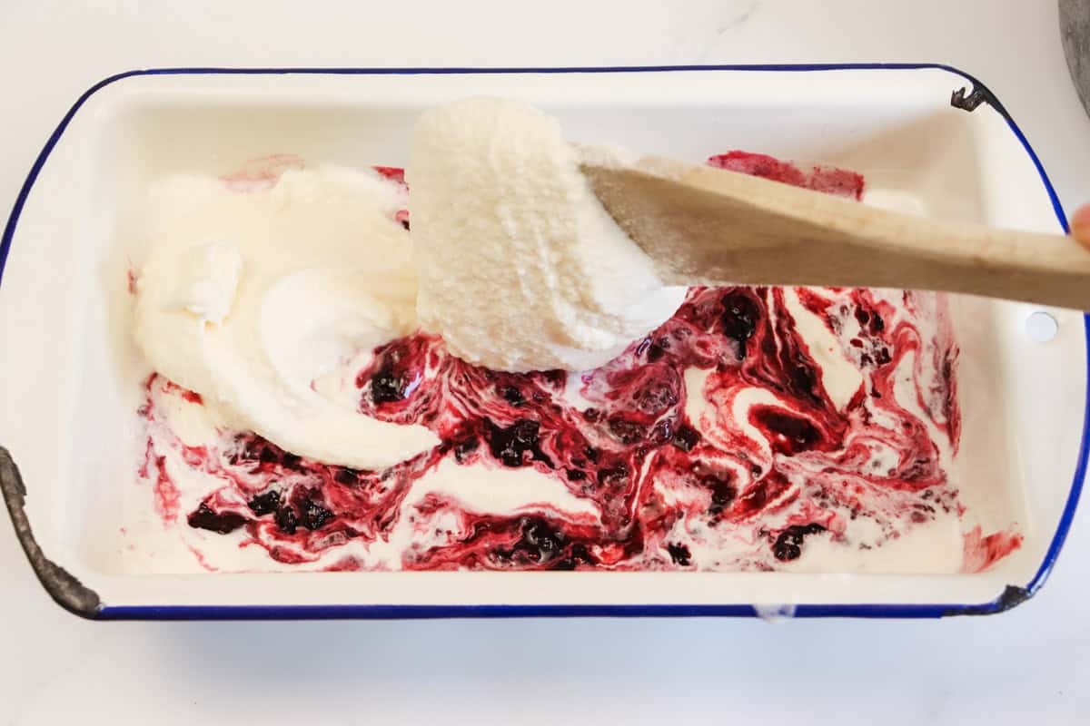 The second layer of ice cream is added to the first layer if swirled berry ice cream