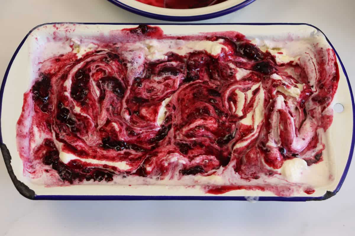 The second layer of berry sauce is swirled through the top layer of ice cream