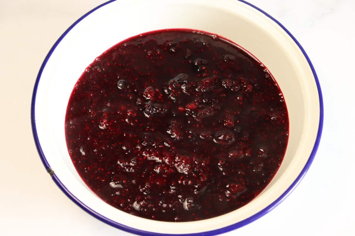 The berry sauce is transferred into a shallow dish to cool