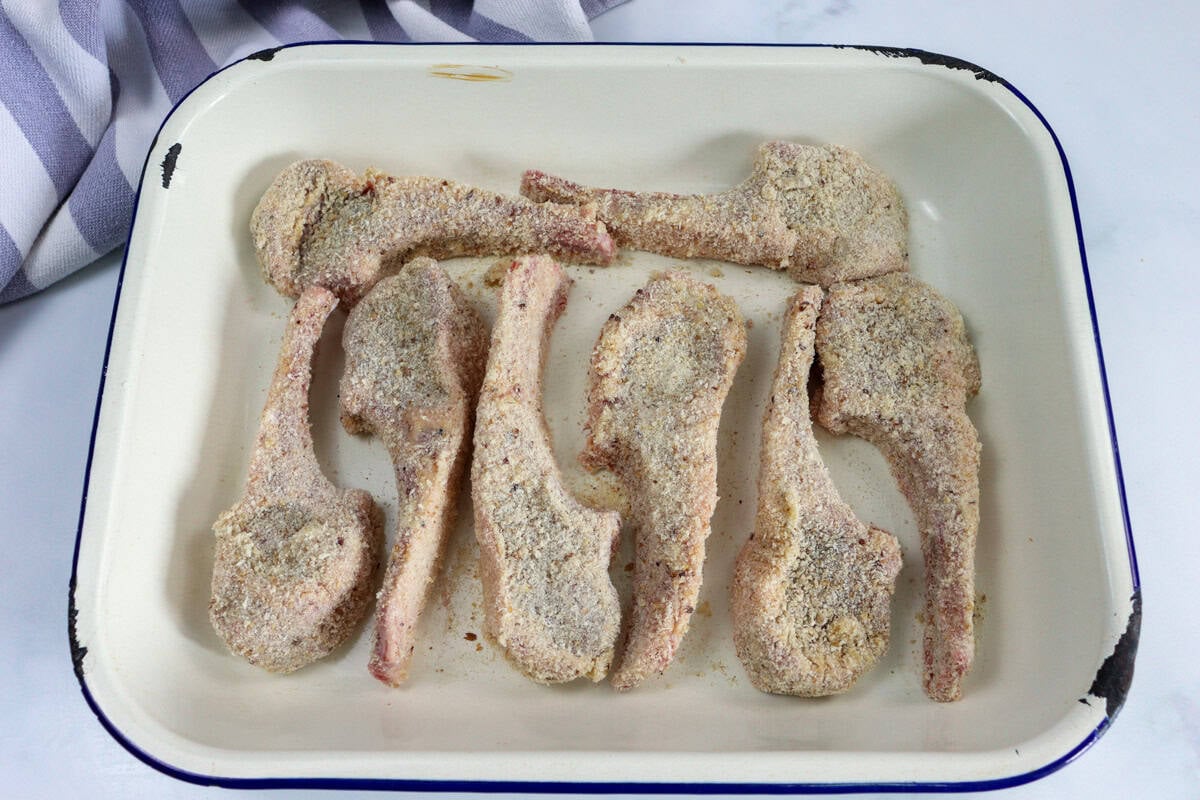 The lamb cutlets are all crumbed and lay on a tray ready to be cooked