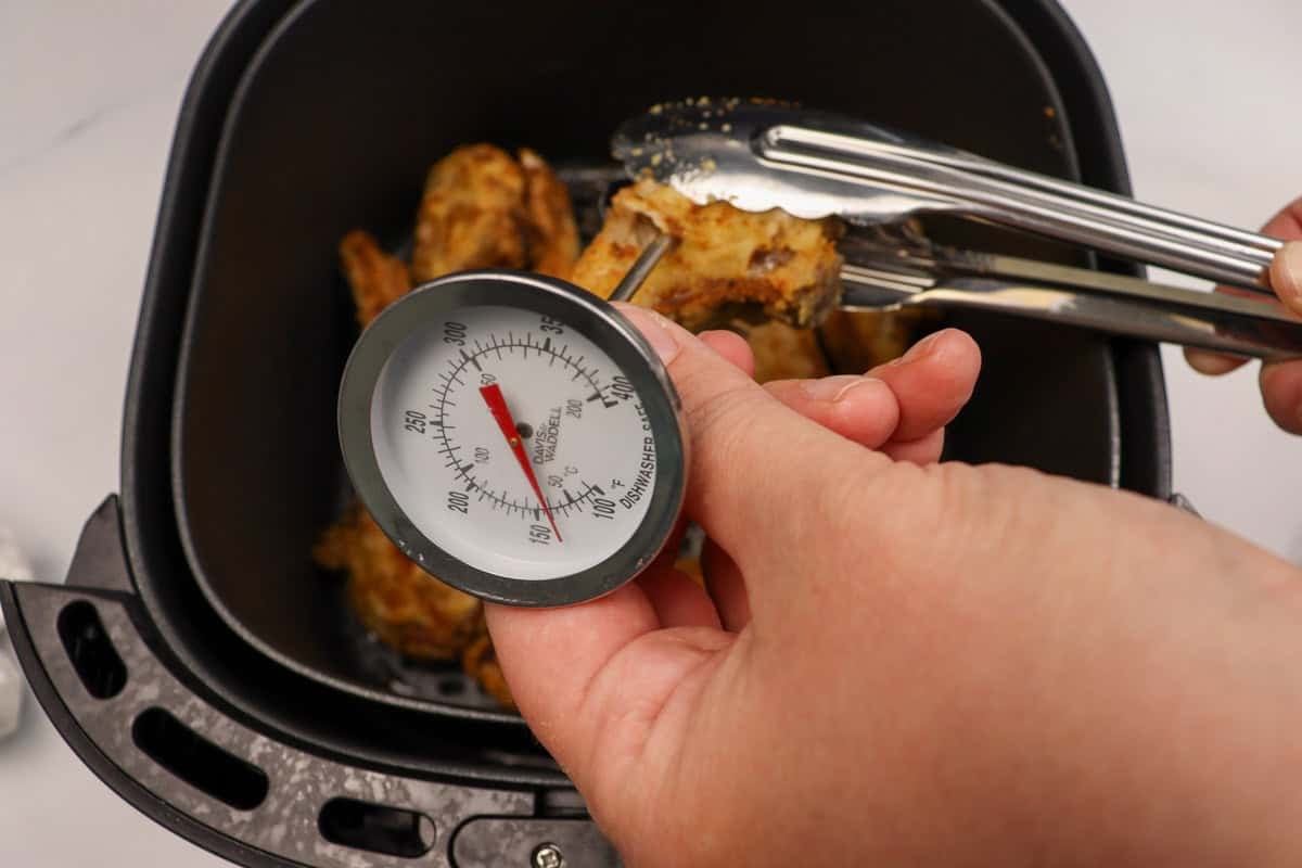 The cooked lamb cutlets are tested with a meat thermometer