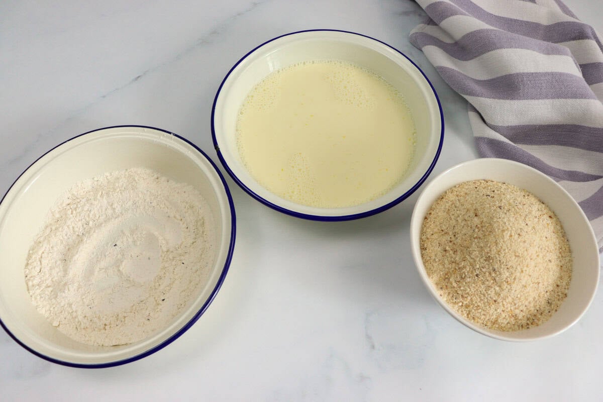 A crumbing station is set up with three dishes: the flour mixture, the egg wash and the breadcrumbs