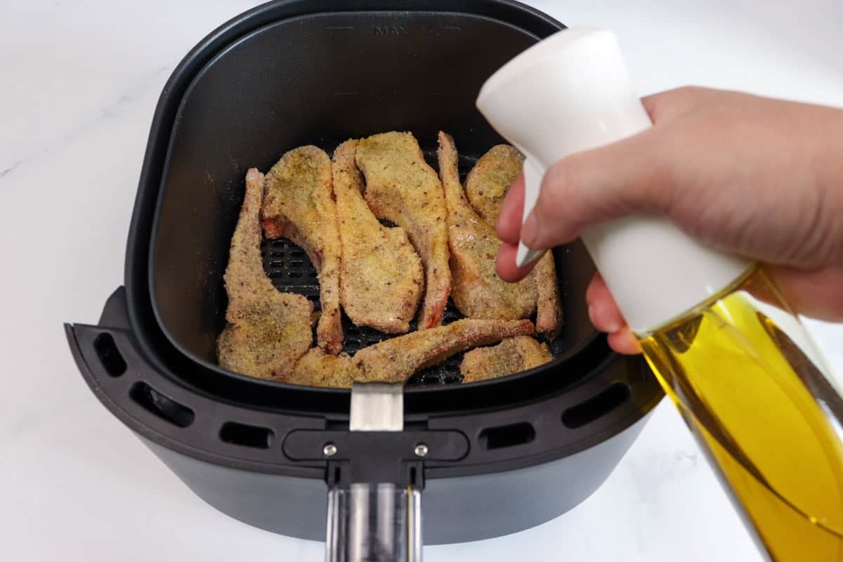 The crumbed lamb cutlets are sprayed with extra virgin olive oil in the air fryer basket prior to cooking
