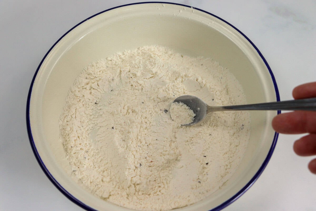 Flour, salt and pepper is combined with a spoon in a shallow dish