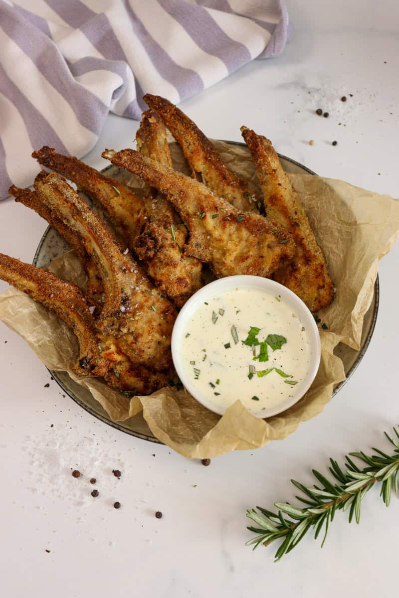 Crumbed lamb cutlets are served in a bowl with a bowl of dipping sauce